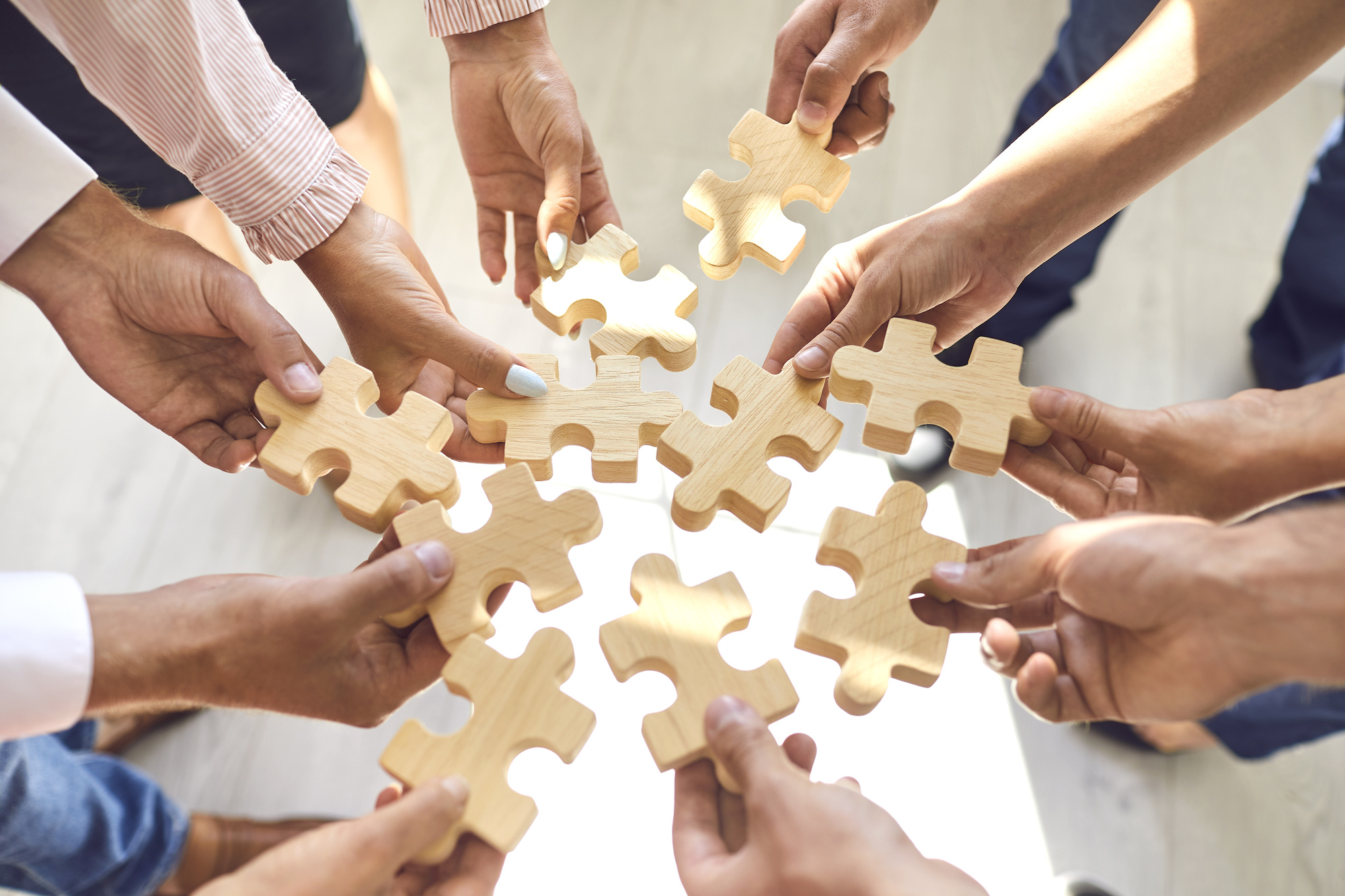 Company employees playing game and joining pieces of jigsaw puzzle during team building activity